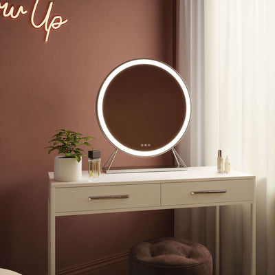 Luxurious Isla Round Hollywood Mirror with silver frame and LED lighting on a vanity table, 60x63cm.