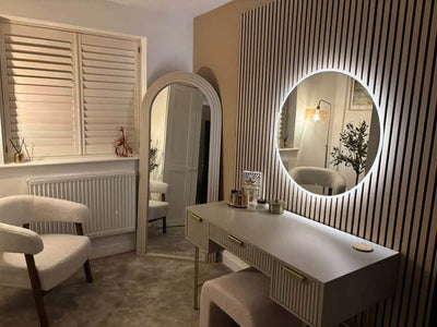 Modern bedroom with a vanity table, round illuminated mirror, and striped wall.