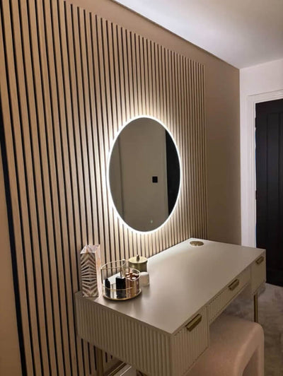 Modern vanity with illuminated round mirror against a slatted wall.