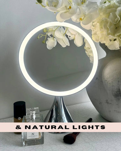 LumiGlam Pro Cosmetic Vanity Mirror in chrome with illuminated LED ring on a vanity table, surrounded by flowers and cosmetics.