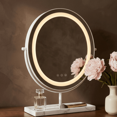 Aurelia LED Vanity Mirror — White & Marble with warm halo ring lighting and flowers.