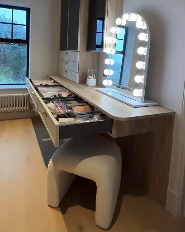 Makeup vanity with a mirror with lights on a dark wall.
