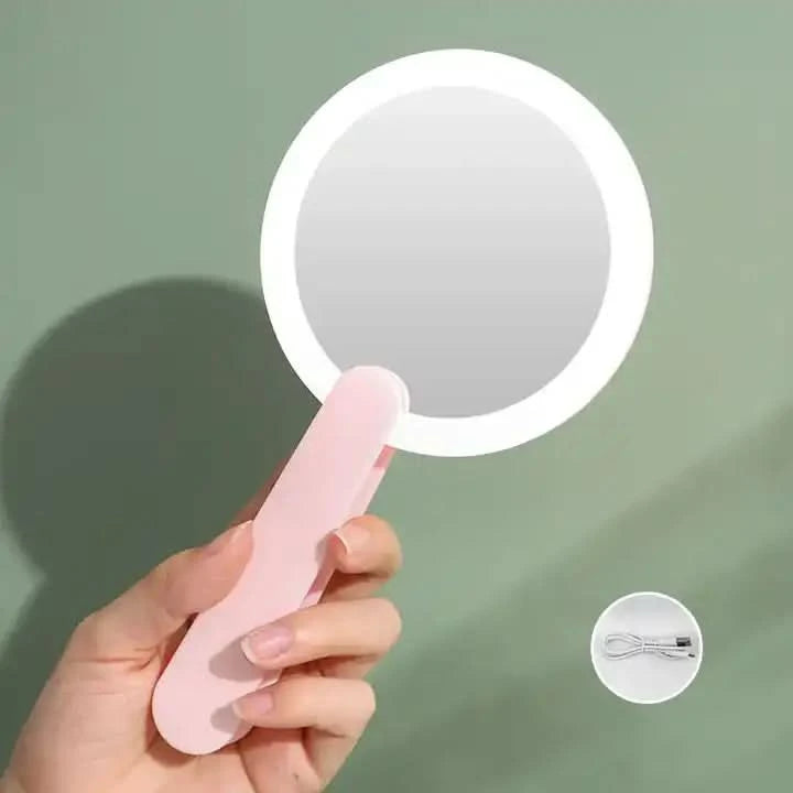 Handheld flip mirror with light pink handle and LED lights for portable beauty care.