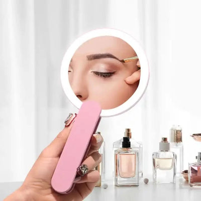 Handheld pink flip mirror with LED light, ideal for travel, showing a clear reflection while grooming, surrounded by beauty products.