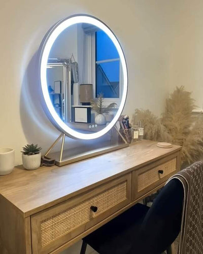 Luxurious gold frame round Hollywood mirror with LED lighting on a wooden vanity table, enhancing elegance and style in a dressing room.