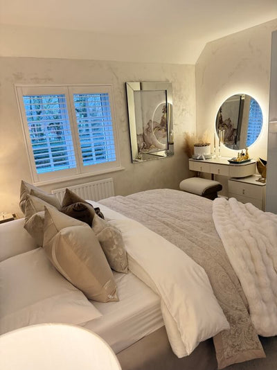 Neatly made bed in a bedroom with decorative pillows and a mirror.