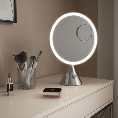 LumiGlam Pro Cosmetic Vanity Mirror in Chrome with illuminated design on table next to makeup tools.