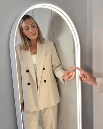 Woman using Sophia Full Length Arch Mirror White Frame with touch-activated lighting.