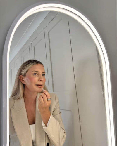 Woman applying makeup in front of Sophia Full Length Arch Mirror White Frame with LED lighting