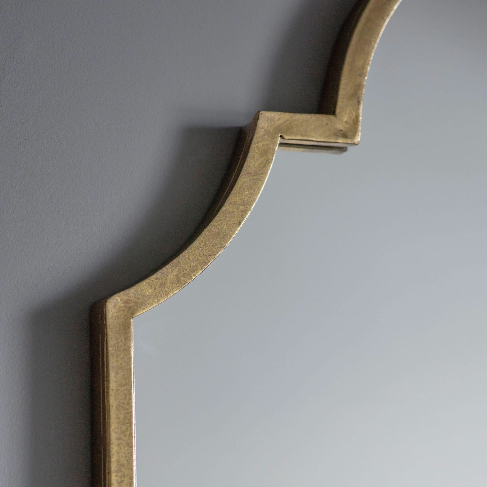 Close-up of Verona Gold Elegant Arch Mirror with brushed gold finish on a gray wall.