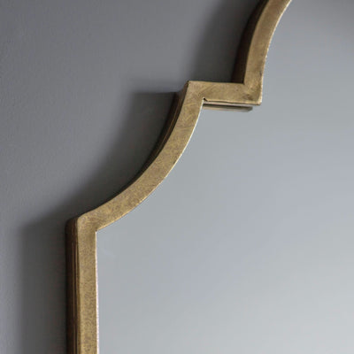 Close-up of Verona Gold Elegant Arch Mirror with brushed gold finish on a gray wall.