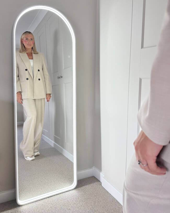 Sophia Full Length Arch Mirror White Frame with LED light, showing a woman standing reflected, perfect for stylish interiors.