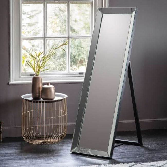 Angled Luna silver cheval mirror with elegant kick stand in a stylish room setting, featuring a decorative side table with a plant and vases.