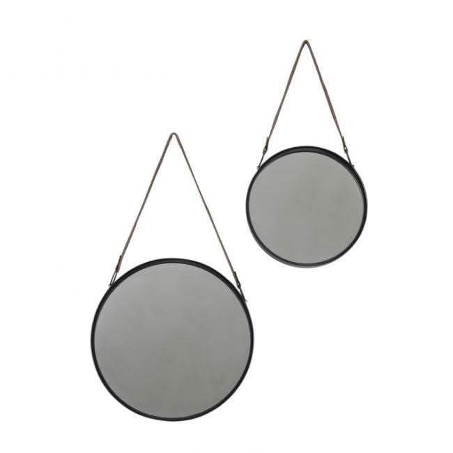 Set of two black metal framed Marston hanging mirrors with faux leather straps on a wall above a modern dining table and plant.