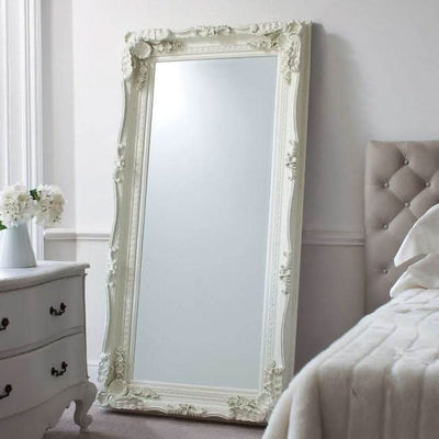 Charles leaner mirror in cream with elegant wood and resin frame, carved details, displayed in a chic bedroom setting.