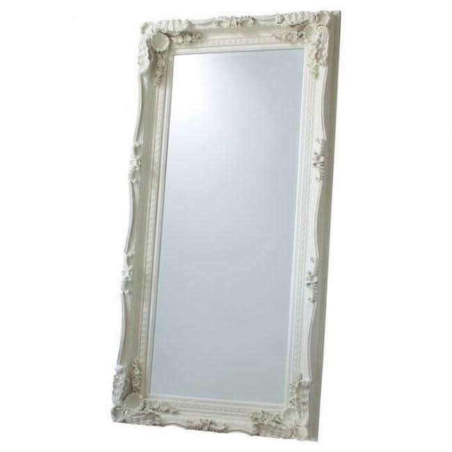 Charles leaner mirror in cream with elegant wood and resin frame, carved details, displayed in a chic bedroom setting.