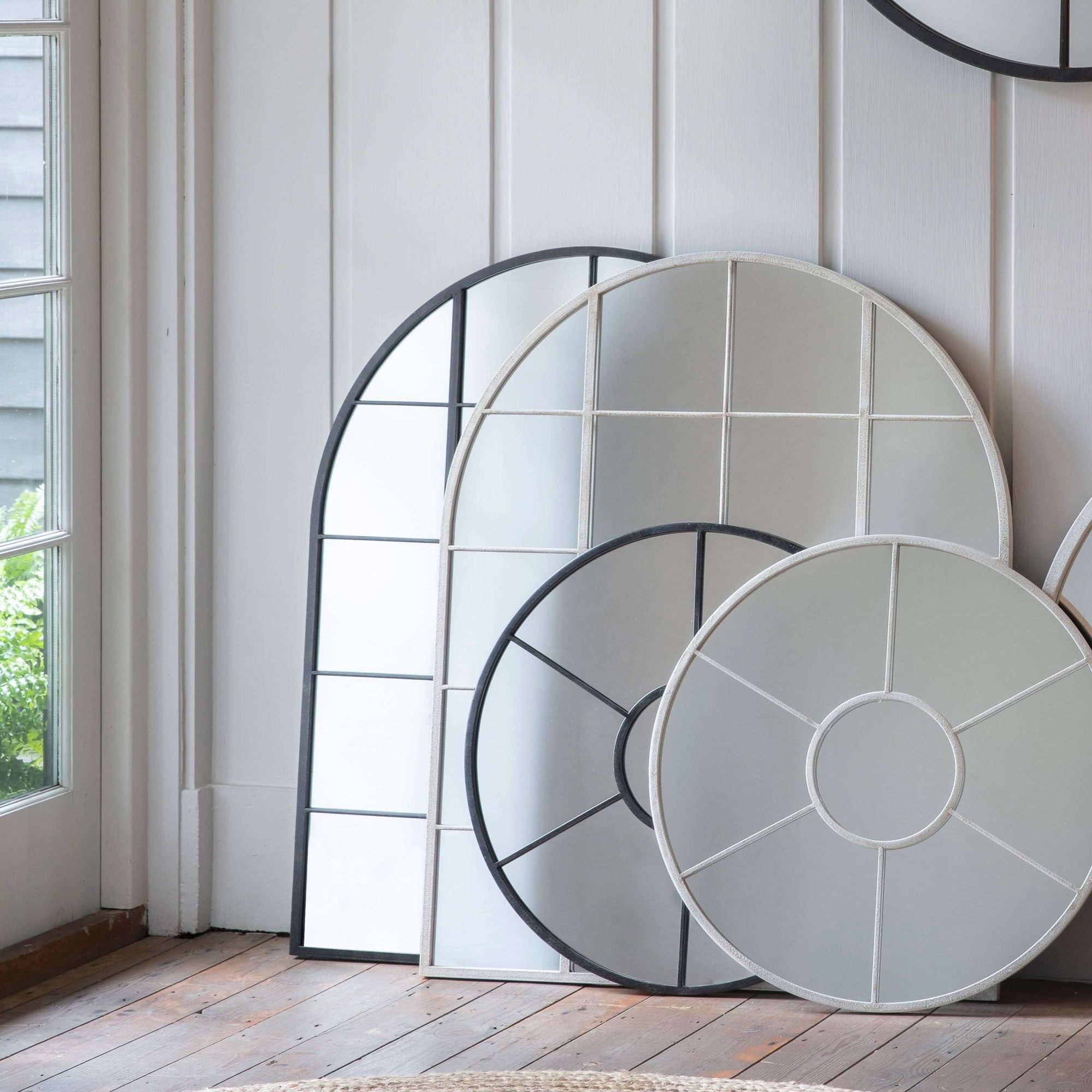 Hailey Black and White Arch Wall Mirror with iron frame, leaning against a wall in a stylish room.