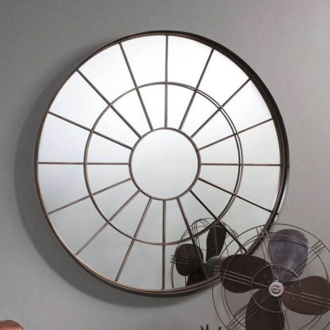 Large round industrial window mirror with bronzed metal frame and textured glass, adding rustic charm to any room decor.