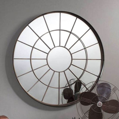 Large round industrial window mirror with bronzed metal frame and textured glass, adding rustic charm to any room decor.