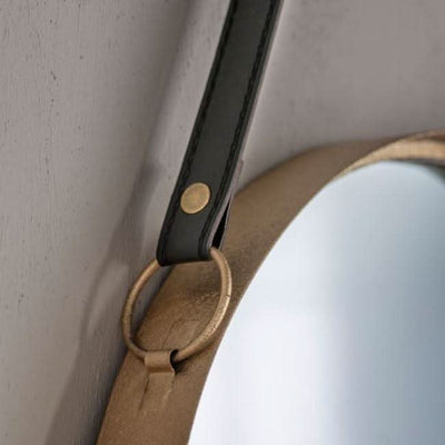 Close-up of a gold metal-framed mirror with black faux leather strap, highlighting elegant details of the set of two Marston Hanging Mirrors.