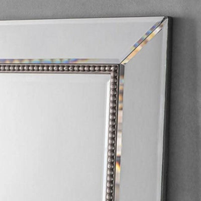Close-up of Regent Rectangular Beaded Mirror with bevelled edges and elegant beading detail on a grey background.