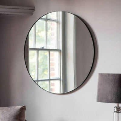 Scandi Large Round Mirror with black metal frame elegantly hanging on a wall, reflecting a window scene. Size 80cm. Ideal for modern decor.
