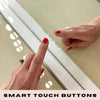 A person with red nail polish touches smart touch buttons on a white Audrey Hollywood Mirror 100x80cm by hollywood mirrors, set beneath glowing studio lighting, with the text SMART TOUCH BUTTONS at the bottom.