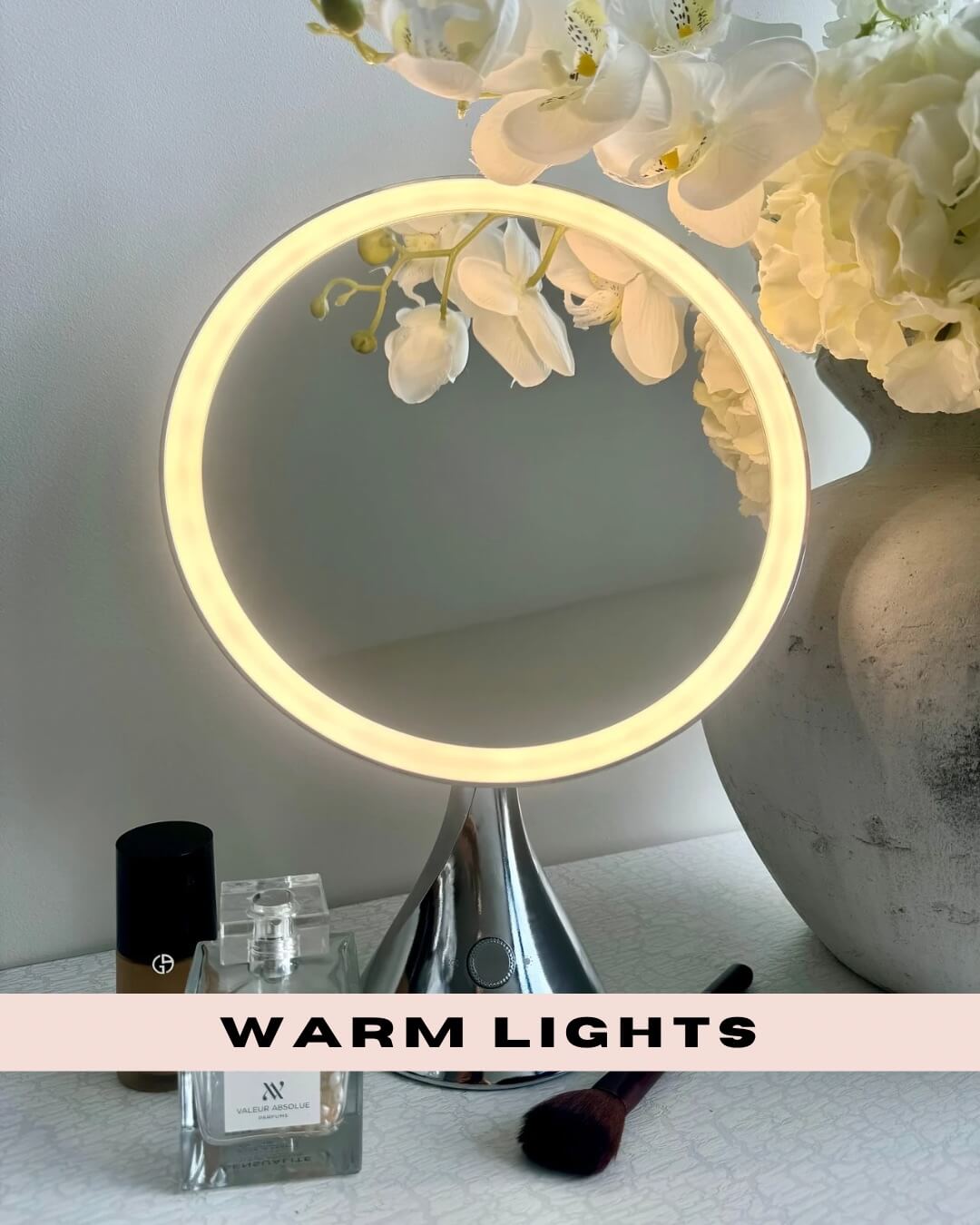 LumiGlam Pro Vanity Mirror in Chrome with warm LED lights, surrounded by flowers, cosmetics, and a makeup brush.