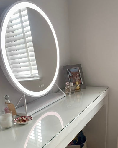 Luxurious white frame round Hollywood mirror with LED lighting on elegant dressing table.