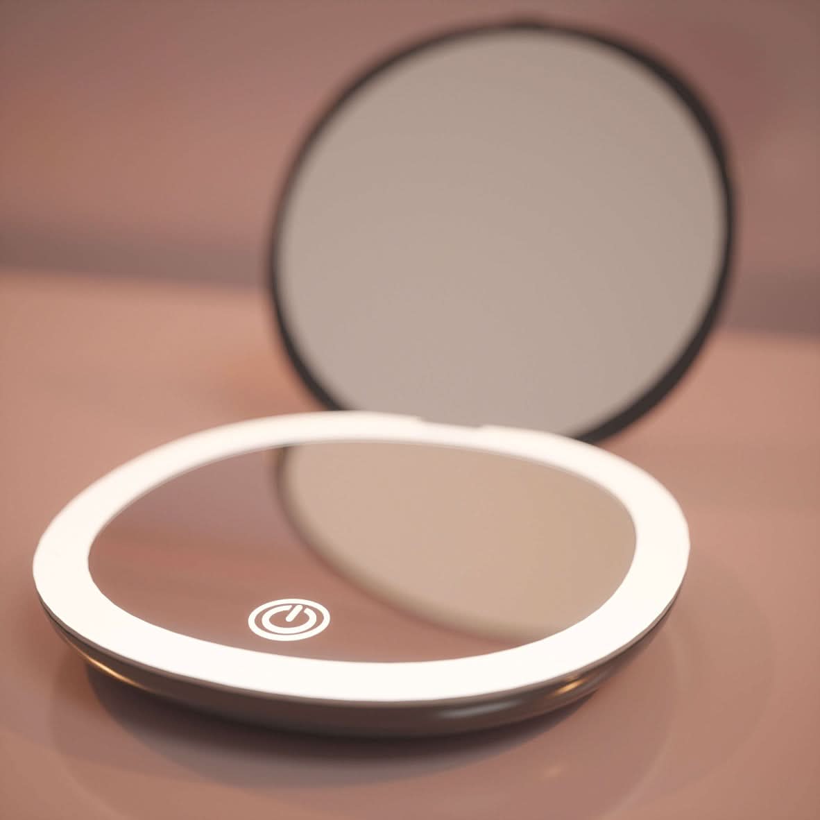The Black Compact Mirror with Light is open on a pink surface, its LED illumination and touch power button reflecting the soft surroundings.