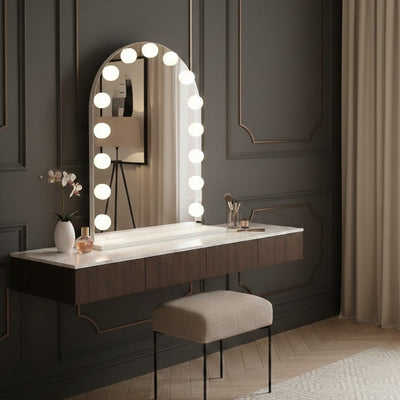 Modern vanity with illuminated mirror against a dark paneled wall.