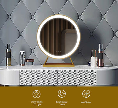 Anne Round Hollywood Mirror Gold 60x63cm features LED lighting, touch sensor controls, and an anti-shatter design on a gold stand atop a textured white dresser with bottles and tubes; tufted gray wall background.