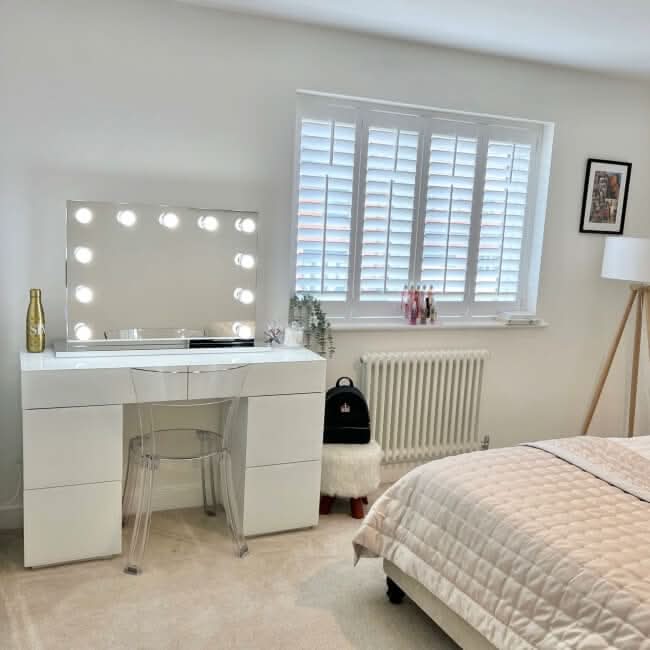 Houston Bluetooth Hollywood Mirror 80x60cm with LED bulbs on a vanity table in a modern bedroom setting for perfect makeup lighting.