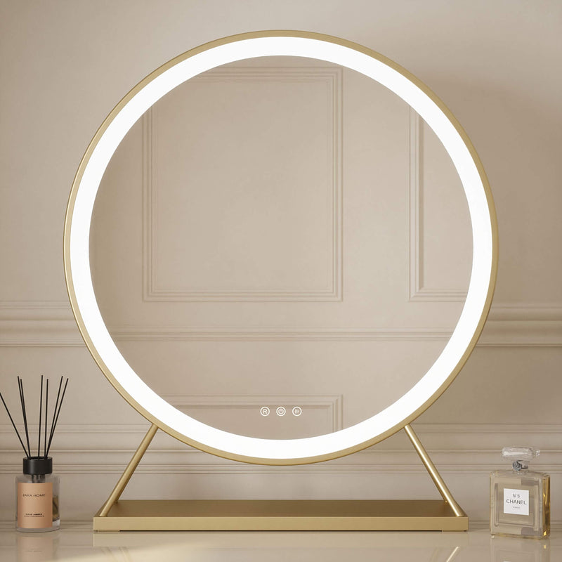 Anne Round Hollywood Mirror Gold 60x63cm with customizable lighting and touch sensor sits on a glossy dresing table desk, reflecting a modern bedroom. A candle and glass box are placed beside this illuminated mirror.