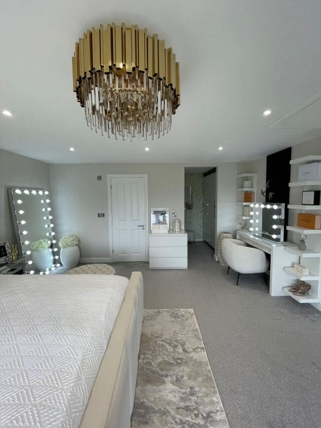 Modern bedroom with Keira Full Length Hollywood Mirror and bright bulbs, large chandelier, and stylish furniture setup.