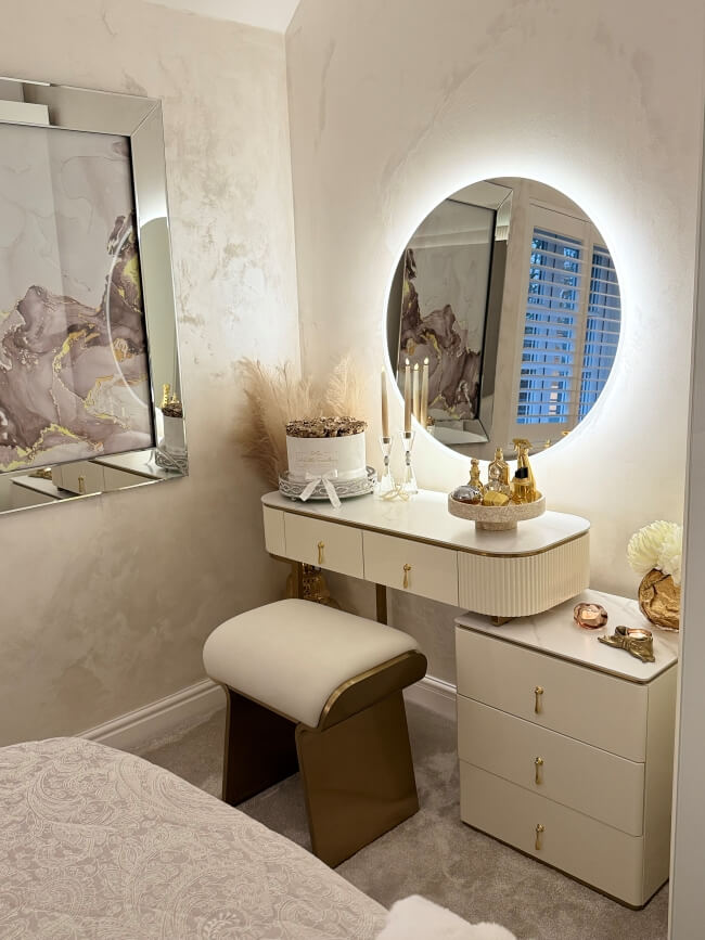 Dressing table with mirror, stool, and decorative items in a bedroom setting.