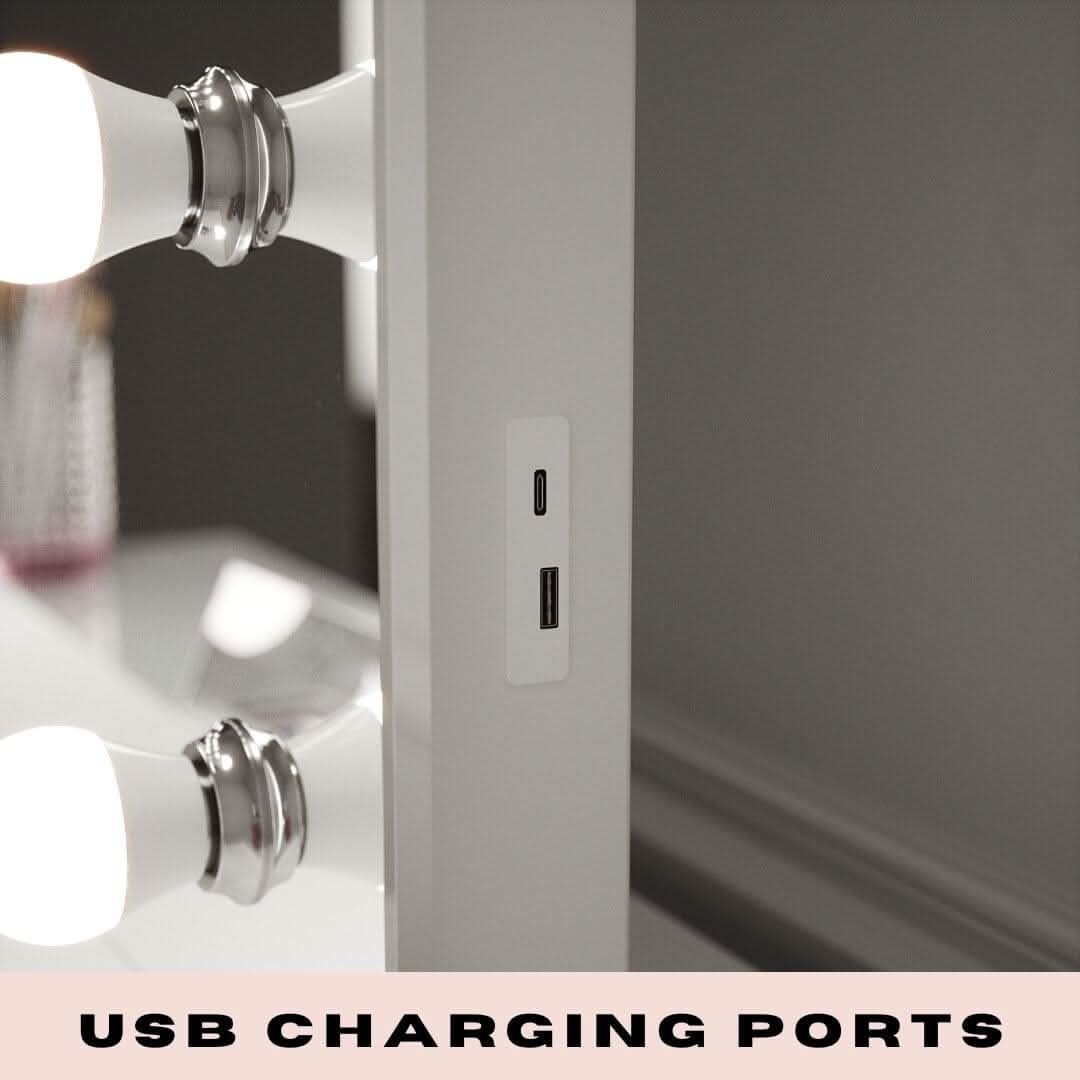 A close-up of the Alicia Hollywood Mirror 60cmx80cm by hollywood mirrors shows built-in USB and USB-C ports on the side, next to illuminated LED bulbs. Text at the bottom reads, USB CHARGING PORTS.