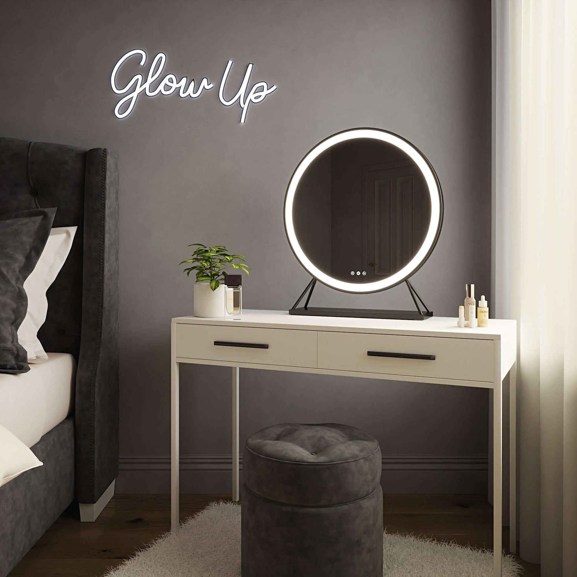 Round black frame Hollywood mirror with customizable LED lighting on a white dressing table next to a 'Glow Up' neon sign.