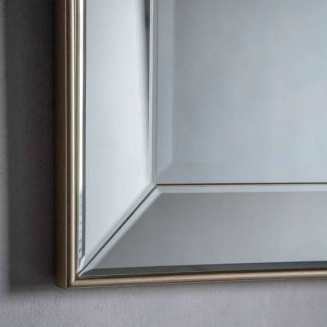 Close-up of Baskin Rectangle Champagne Mirror with elegant beveled frame detail, reflecting light in a luxury setting.