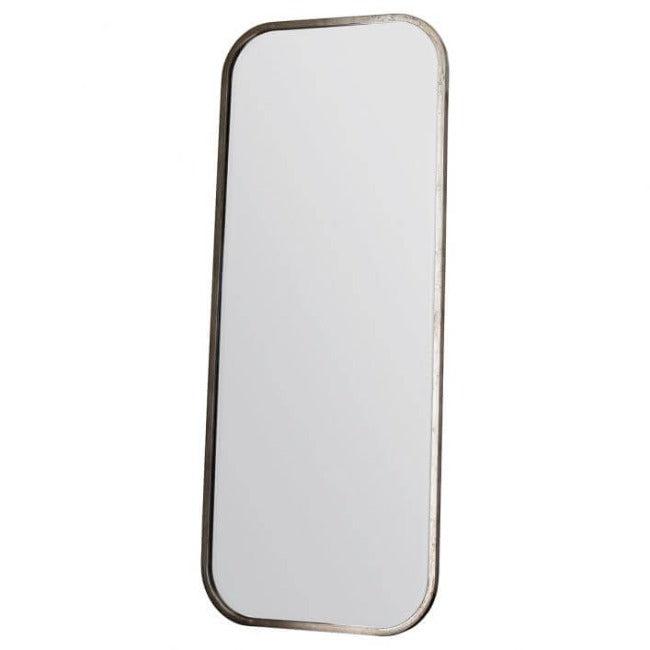 Distressed Champagne Leaner Mirror with streamlined metal frame, enhancing elegant home décor next to a brass lamp.