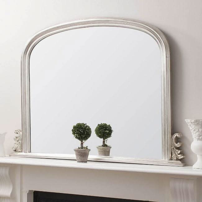 Dome Overmantle Mirror in Silver with vintage-inspired dome top and bevelled glass on a fireplace mantle, adding luxury and elegance to interiors.