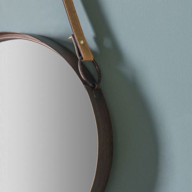 Close-up of bronze-framed Marston hanging mirror with black faux leather strap, perfect for home decor.