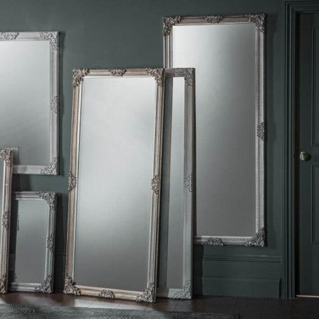Stone gray large baroque style mirrors with ornate frames, arranged against an elegant green wall, enhancing sophisticated interior design.